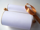 Blank white paper scroll for handwritten wedding vows, gold finials and accents, with white presentation box